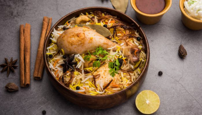 Restaurant style Spicy Chicken Biryani in wooden bowl with Raita and salan, Popular Indian or Pakistani Food